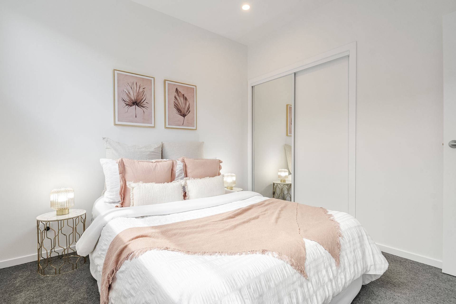 A bedroom with a bed , nightstand , mirror and sliding wardrobe.