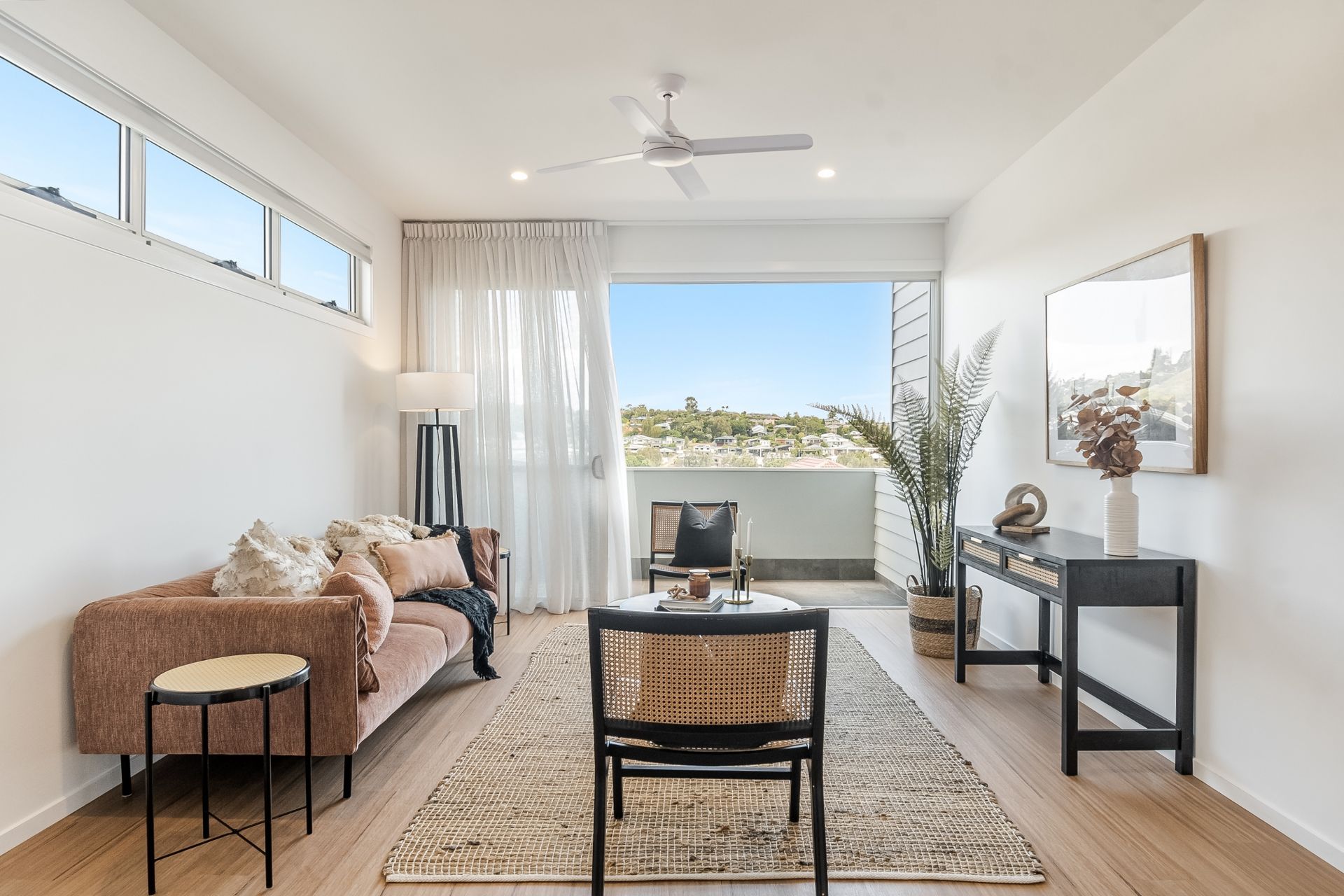 a living room with a couch and chairs and a ceiling fan .