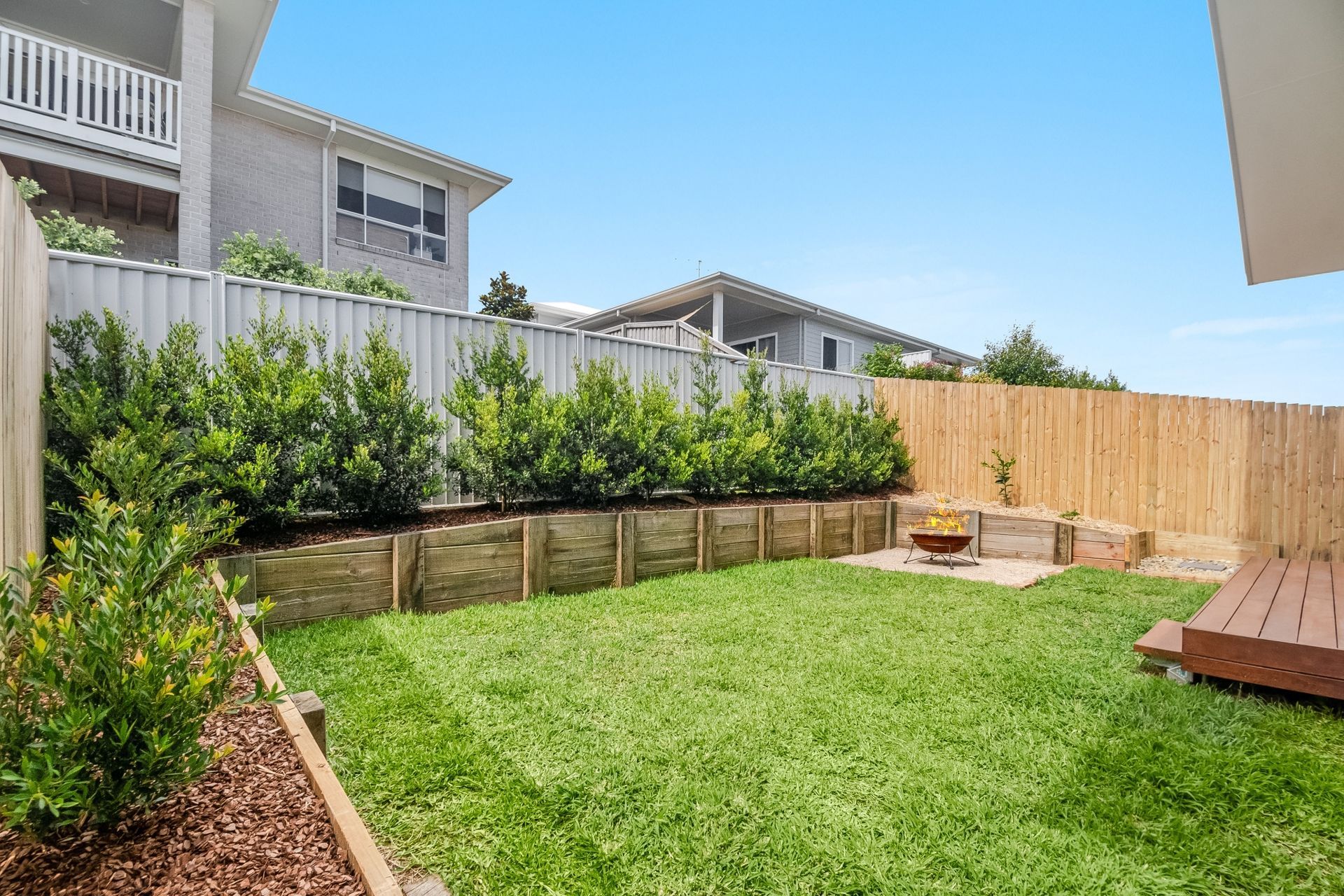 A backyard with a wooden fence and a fire pit.