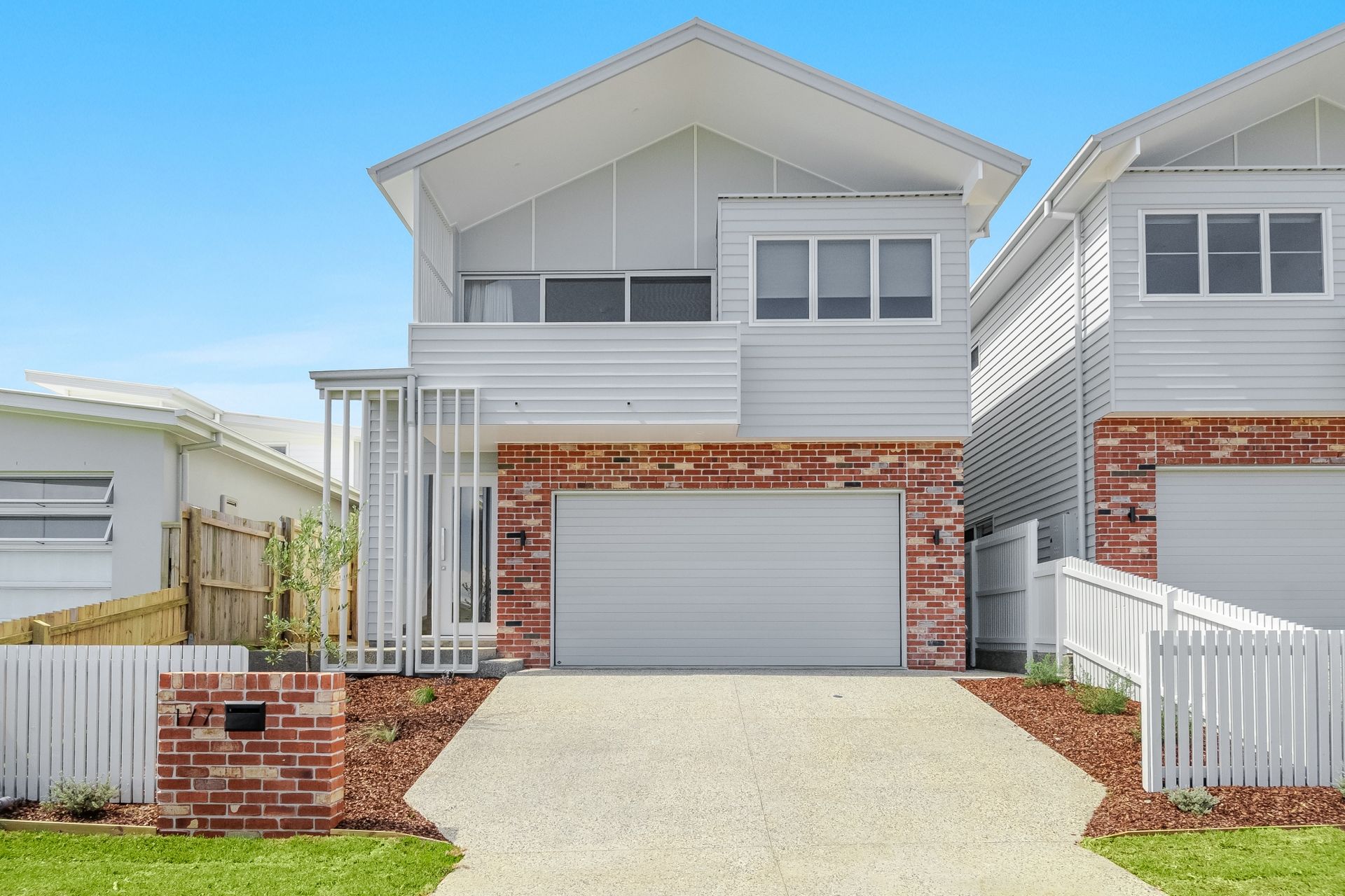 a white house with a brick wall and a white garage door .