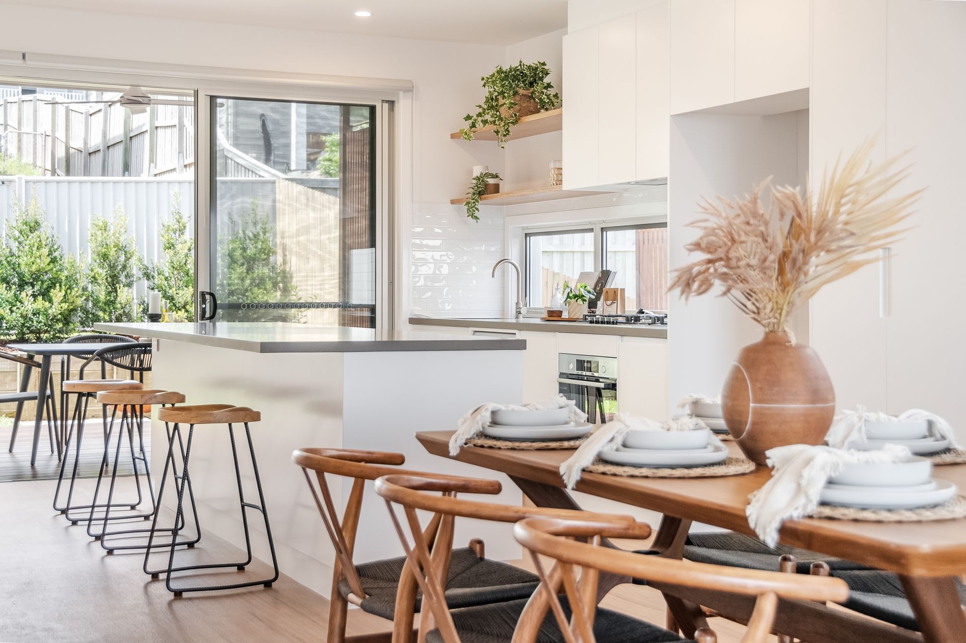 a dining room with a table and chairs and a kitchen in the background .