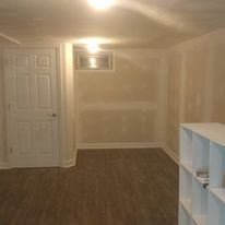 A wooden deck is sitting in the grass in front of a brick house.