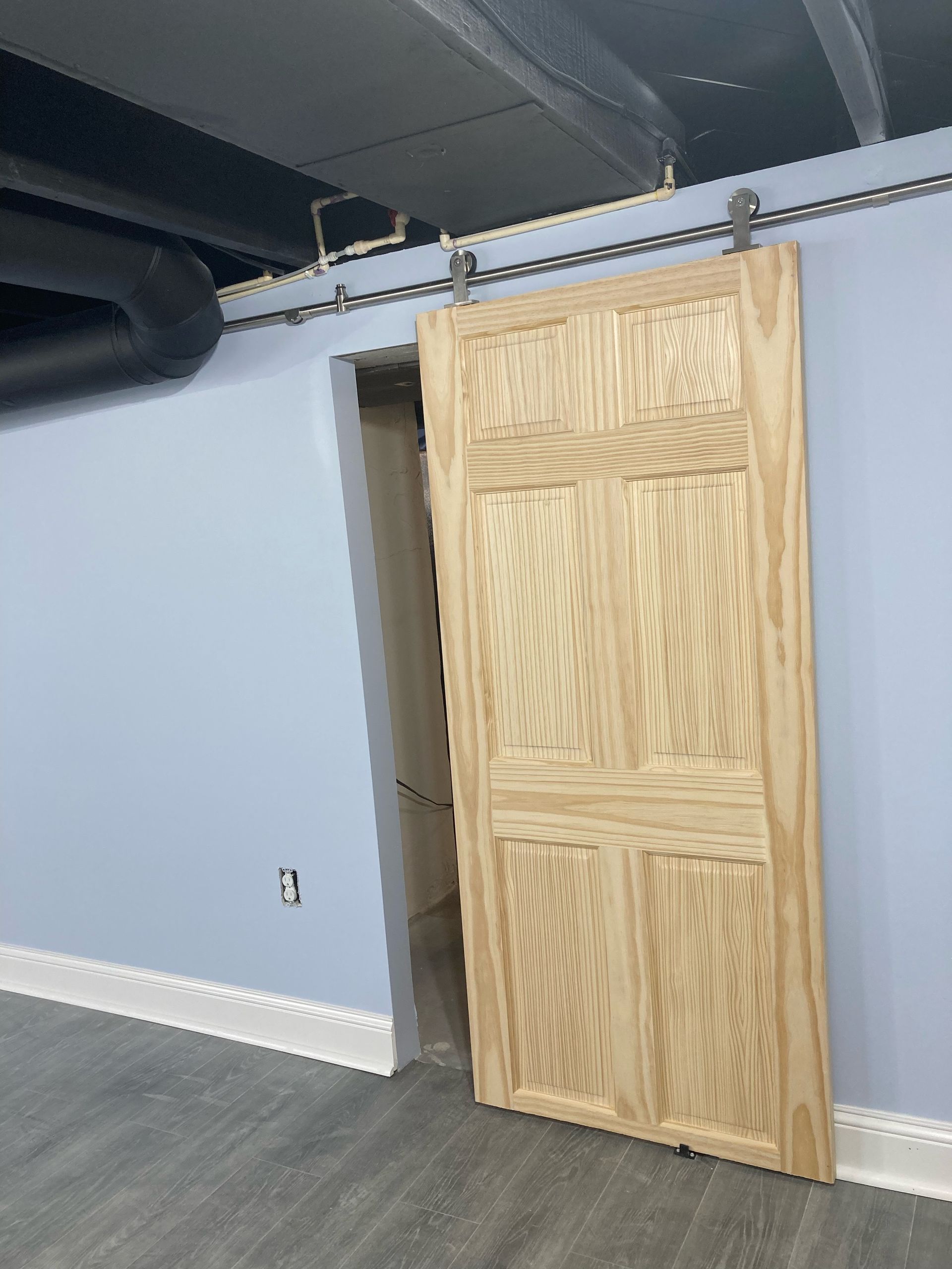 An empty basement with stairs and a black ceiling.