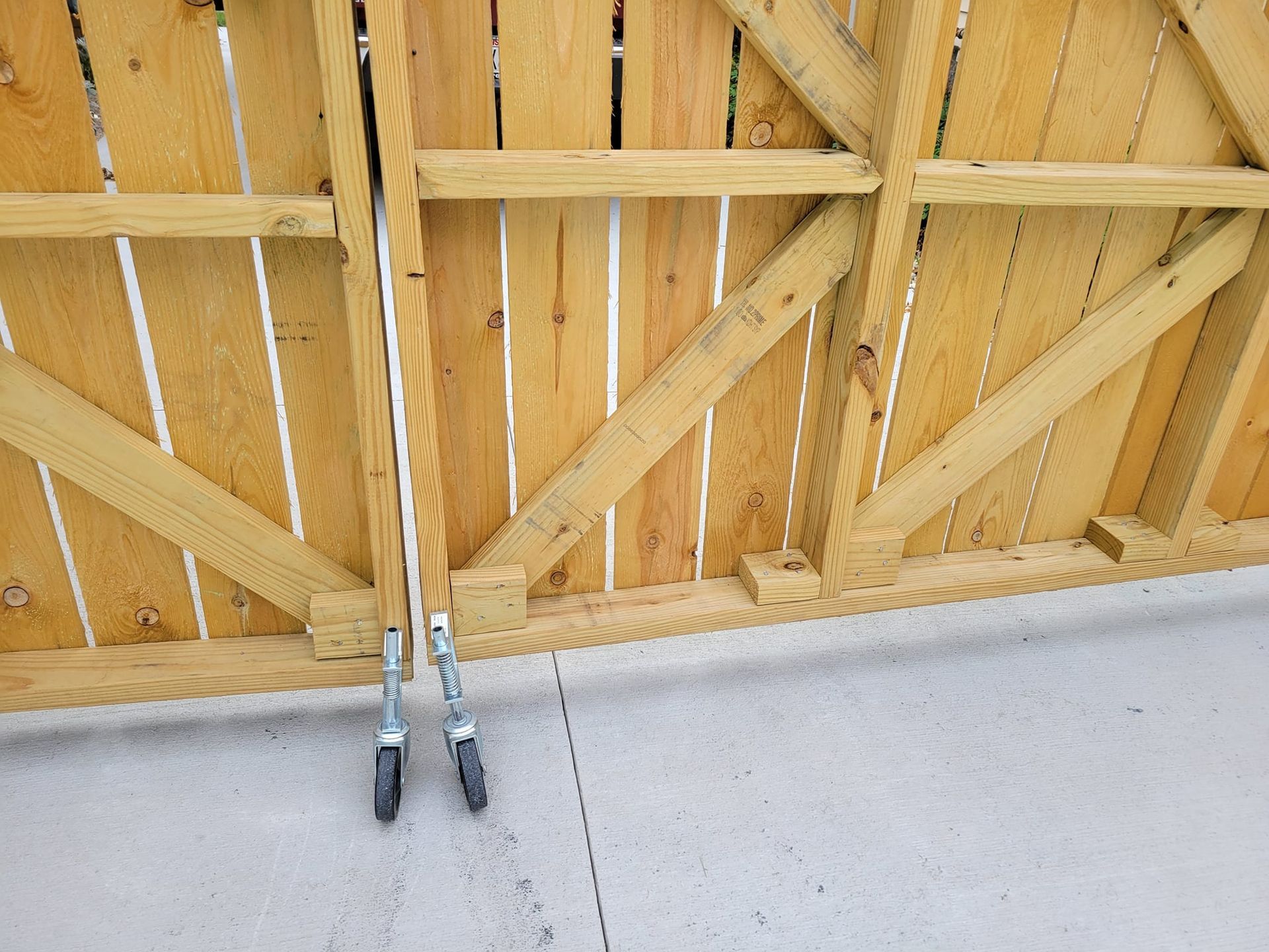 A wooden fence with wheels attached to it is sitting on the ground.