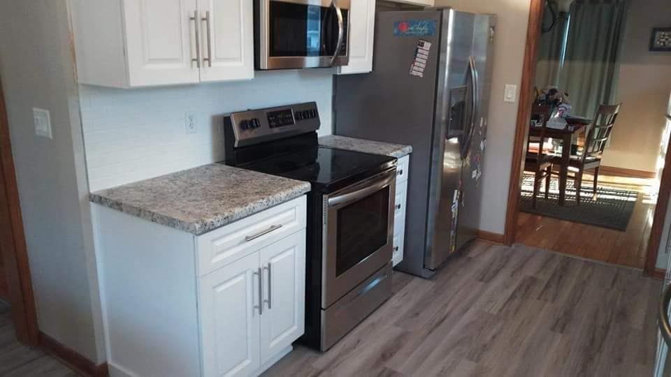 A kitchen with a stove , refrigerator , microwave and sink.