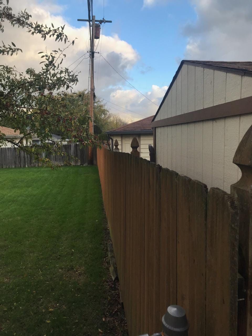 A wooden fence surrounds a lush green yard in front of a house.