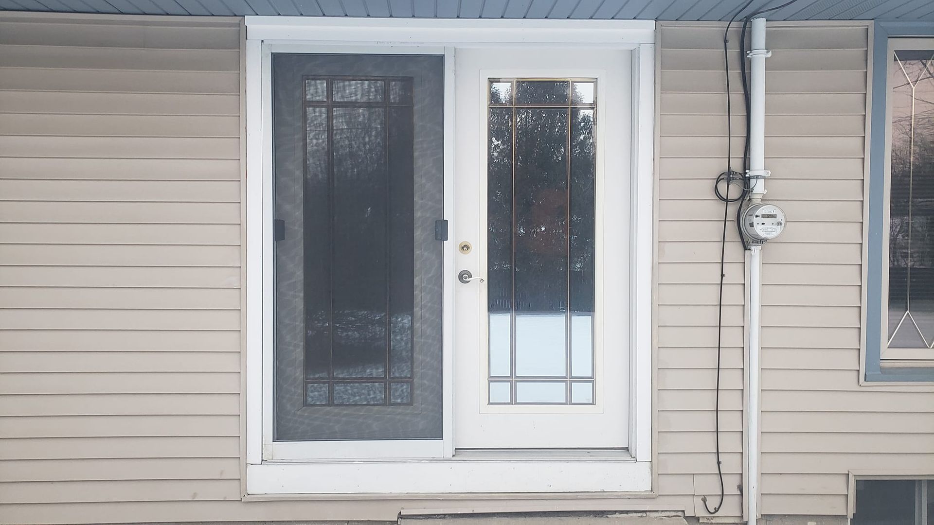 A white door with a screen on it is on the side of a house.