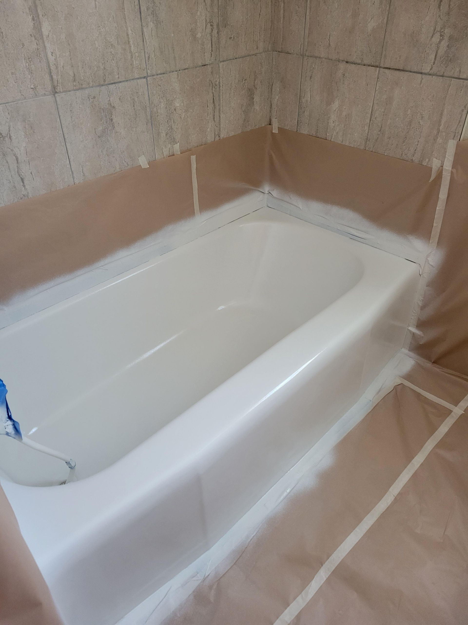 A white bathtub is being painted in a bathroom.