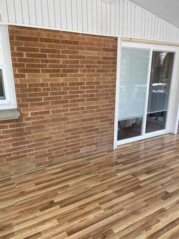 There is a brick wall and a wooden floor in the room.