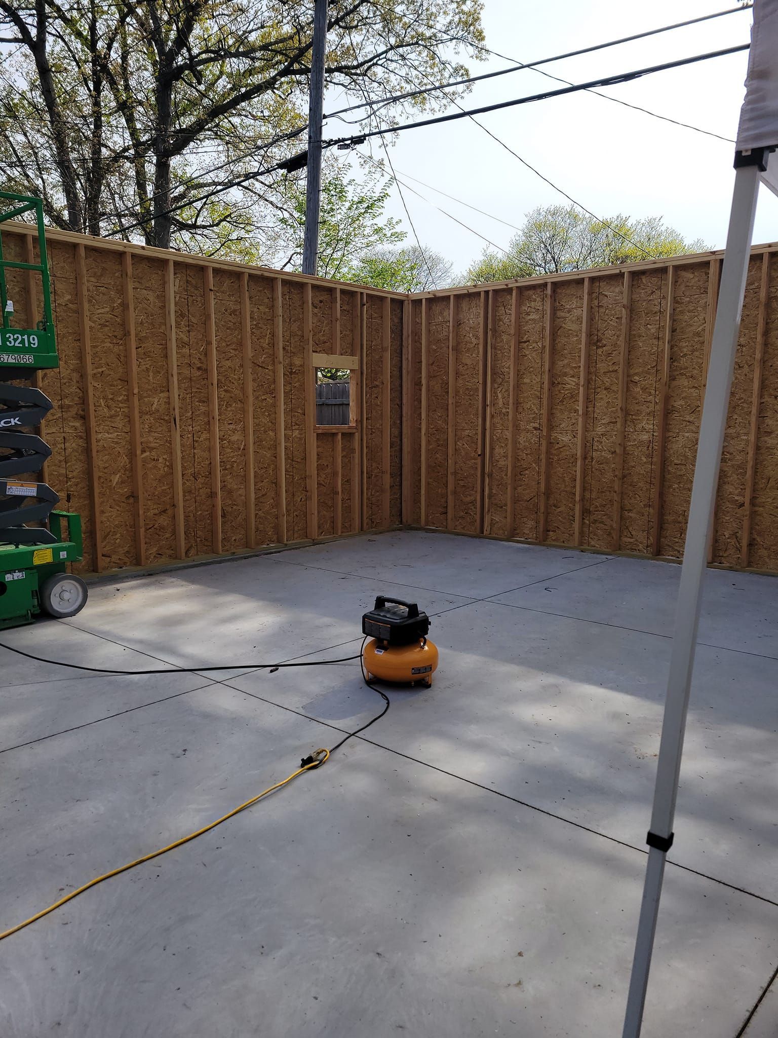 A vacuum cleaner is sitting on the floor of a garage under construction.
