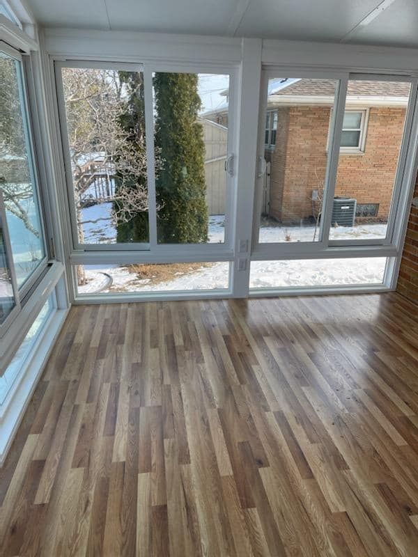 An empty room with a wooden floor and lots of windows.