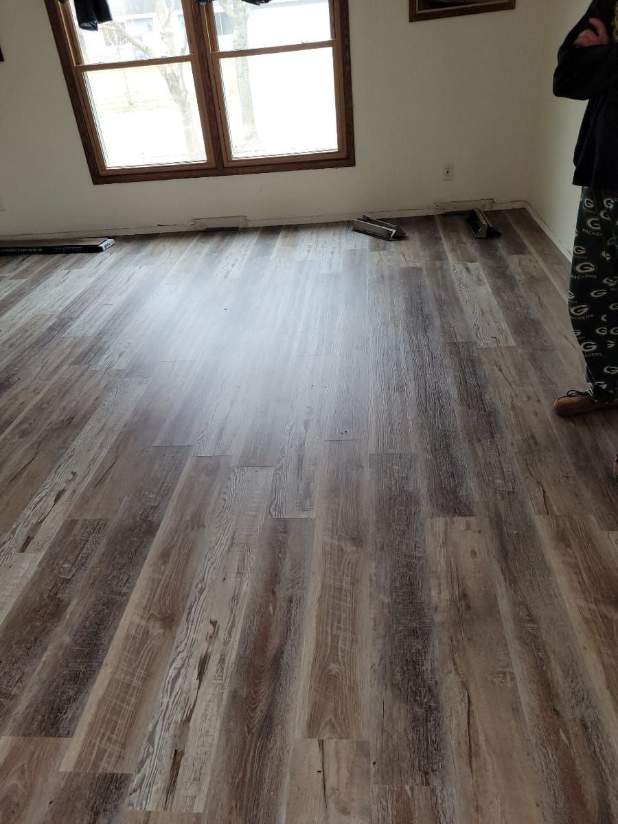 A person is standing in a room with a wooden floor.