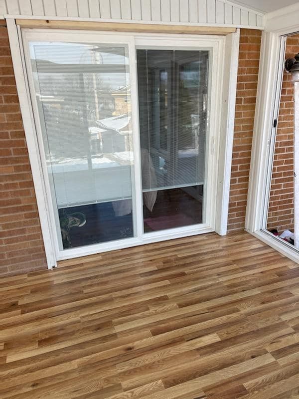A porch with a sliding glass door and a wooden floor.