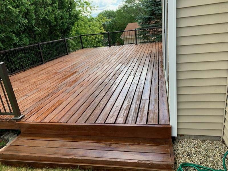 A wooden deck with stairs and a railing next to a house.
