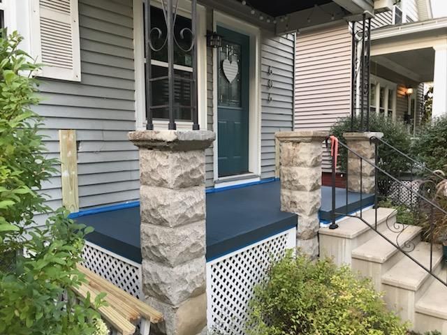 The front porch of a house is being painted blue.