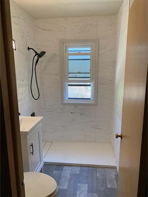 A bathroom with a toilet , sink , shower and window.
