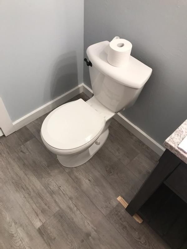 A toilet with a roll of toilet paper on top of it in a bathroom.