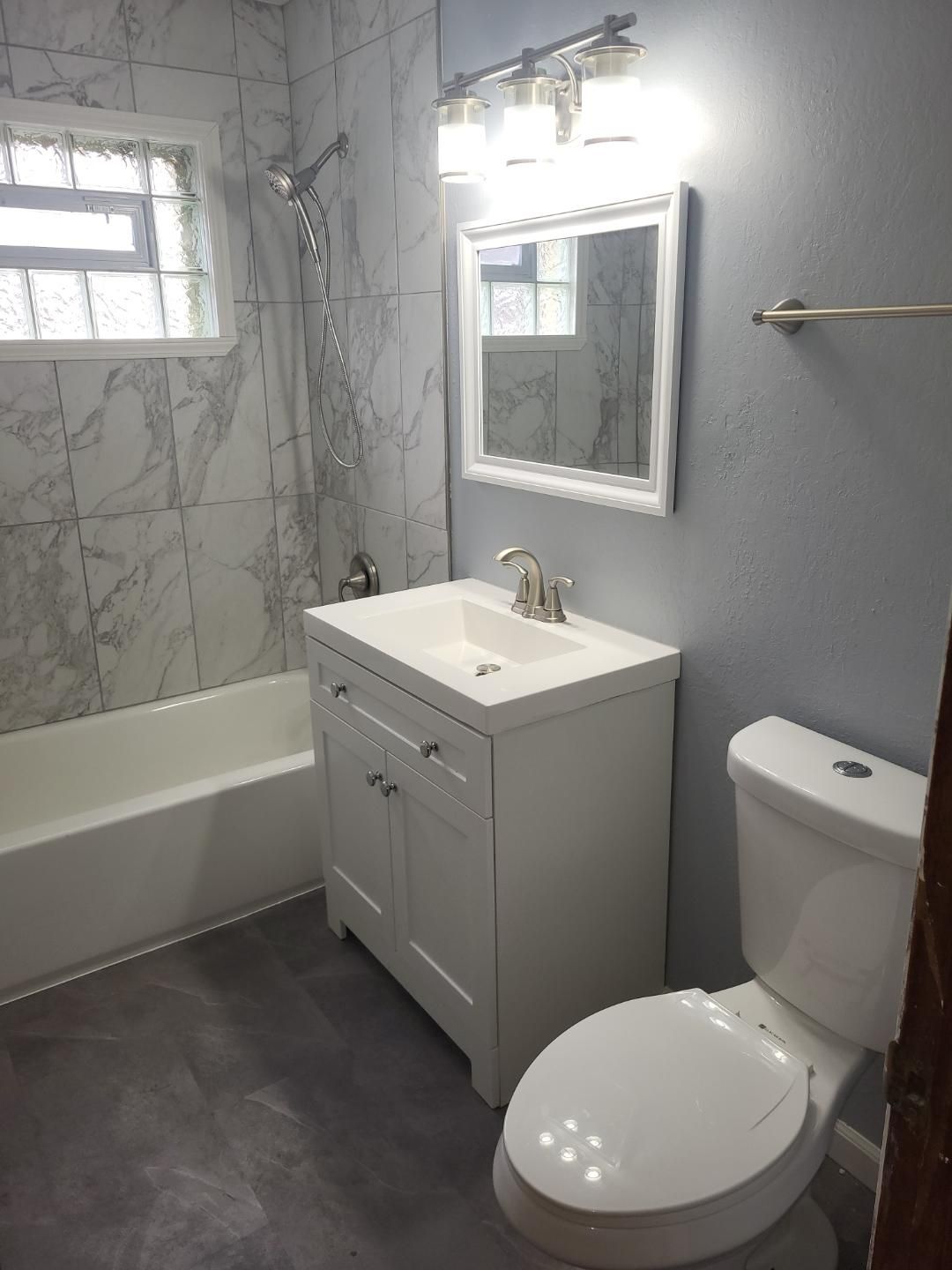A bathroom with a toilet , sink , tub and mirror.
