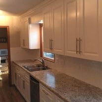 A kitchen with white cabinets , granite counter tops , a sink , and a window.