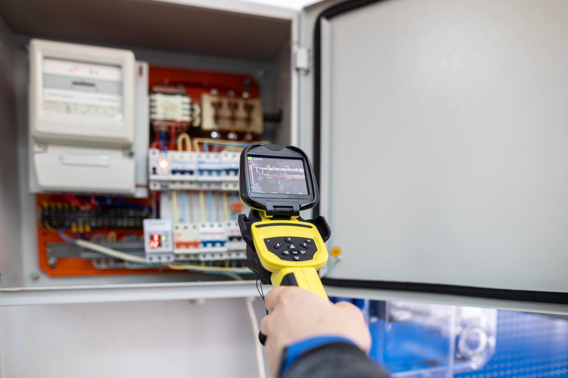 Thermal camera inspecting an open electrical control panel with wiring and circuit breakers