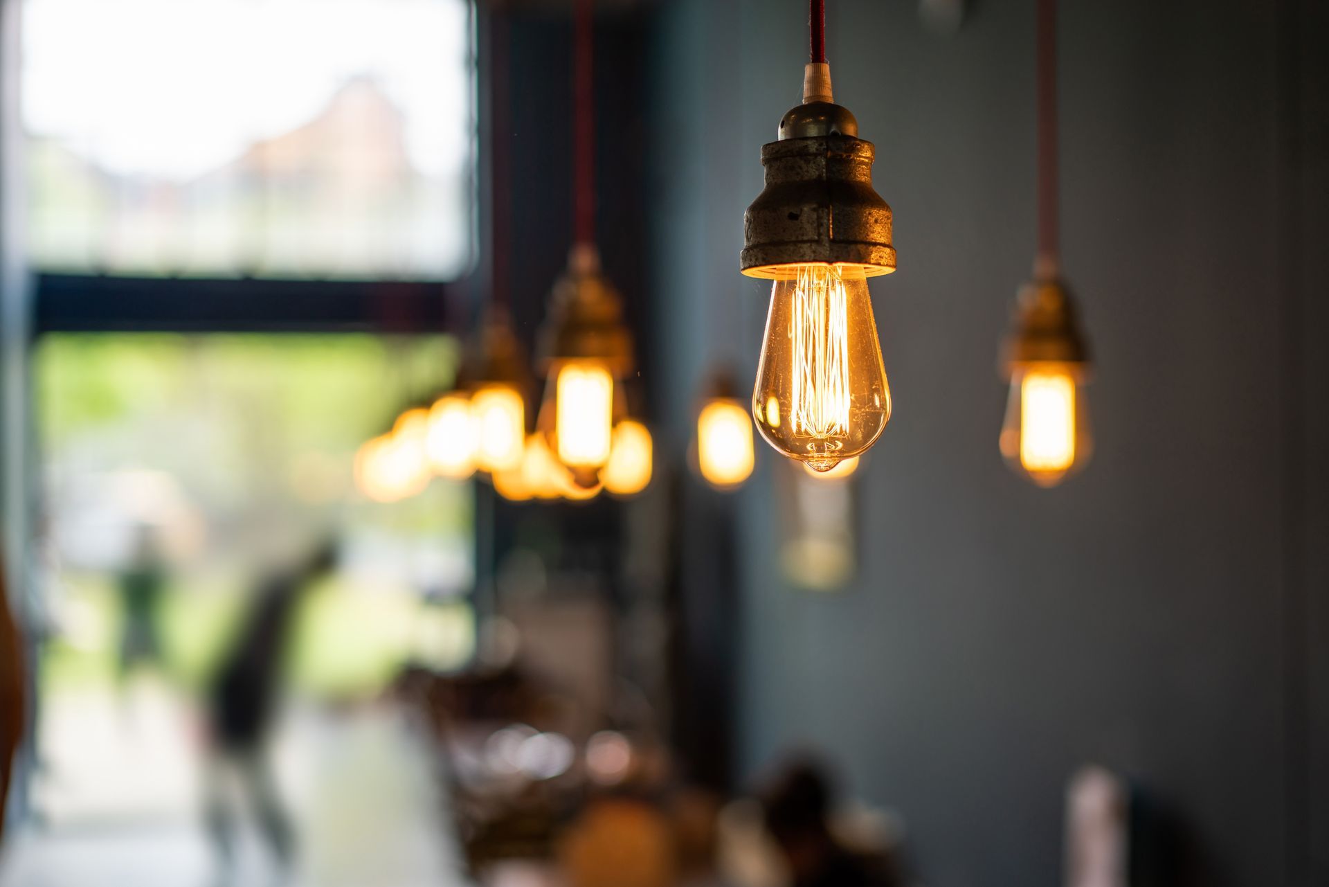 Close-up of glowing Edison-style pendant lights hanging in a dim, out-of-focus indoor space.