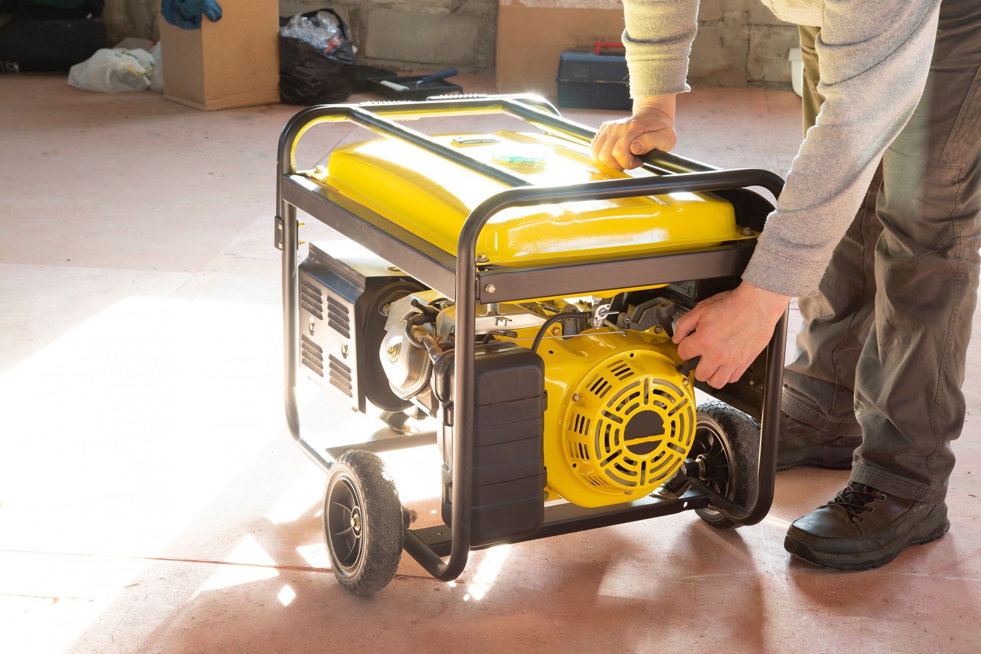 Person starting a yellow portable generator in a garage-like space.