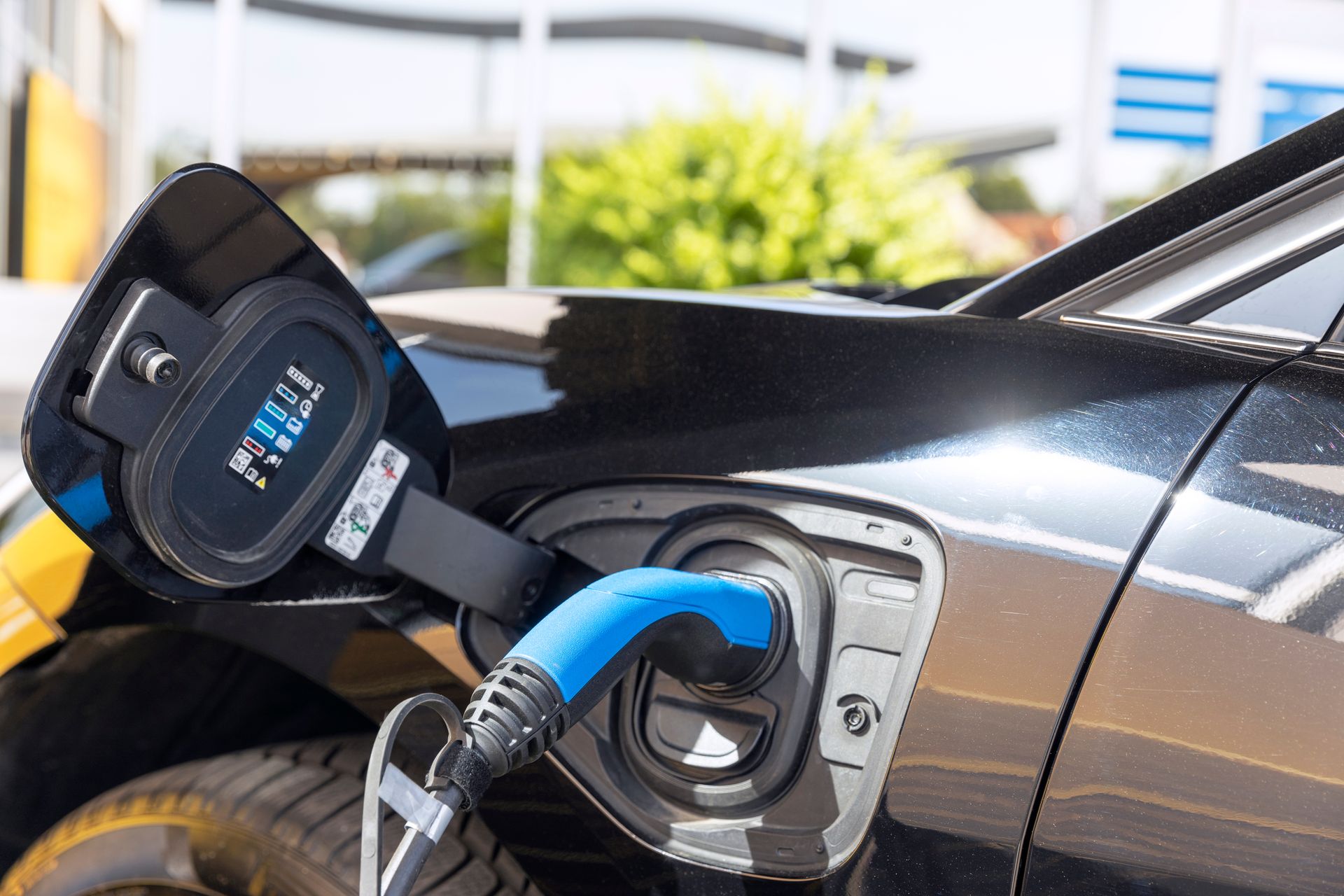 Electric car charging at a station with a blue plug connected to the port