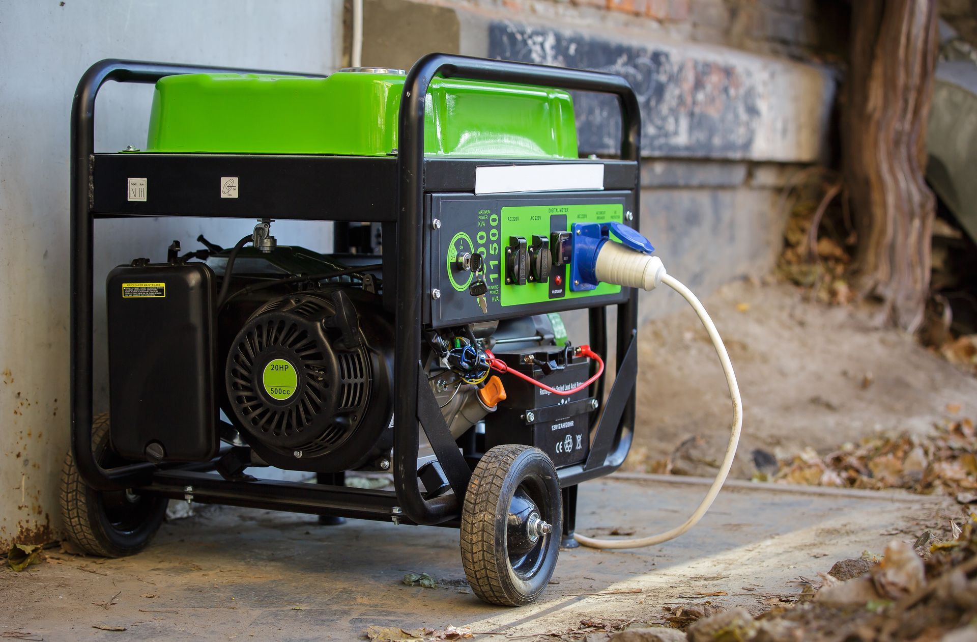 A portable, green and black petrol generator with wheels and a power cable attached, sitting on a concrete surface.