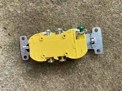 Yellow electrical outlet or switch assembly on a gray surface.