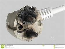 A white electrical plug with severe burn damage and melted plastic casing.