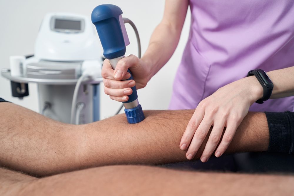 Therapist Using a Blue Device on A Patient's Leg for Treatment — My Chiropractor Mackay City in Proserpine, QLD