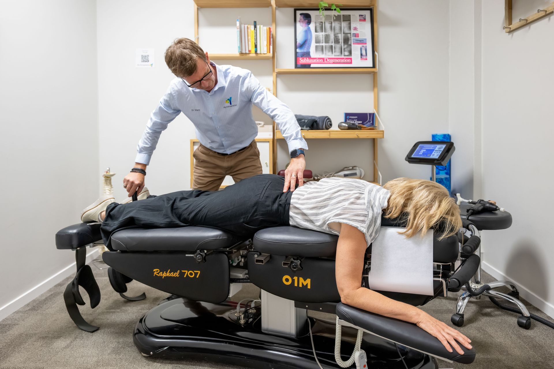 Chiropractor examining a patient lying on a treatment table in an office — My Chiropractor Mackay City in Mackay, QLD