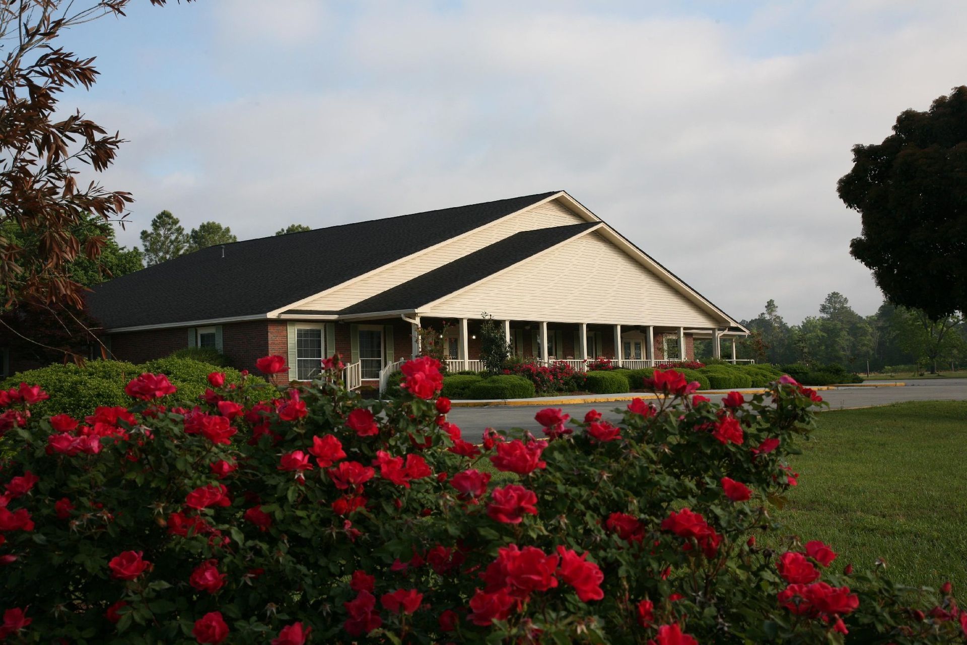 Building with a black roof, surrounded by red roses in bloom.