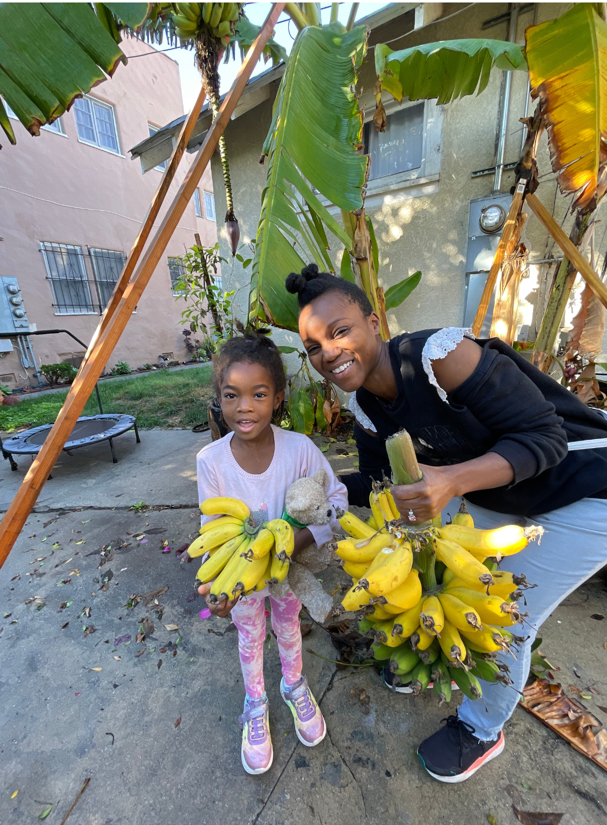 A woman and a little girl are holding a bunch of bananas. Eden Creative Arts - Private Christian Micro School 