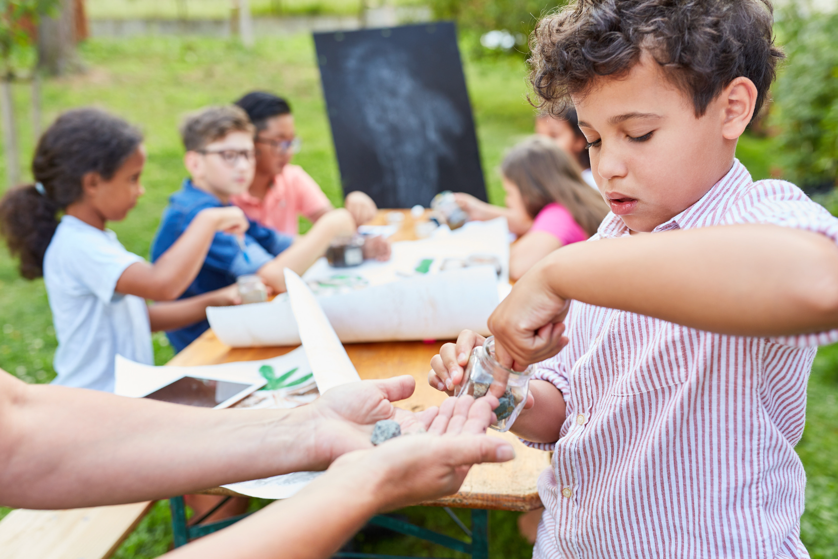 A group of children are sitting at a table playing with rocks. Eden Creative Arts - Private Christian Micro School