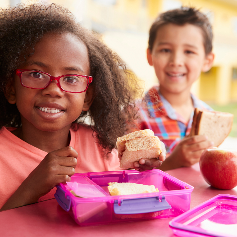 A boy and a girl are sitting at a table eating lunch.
