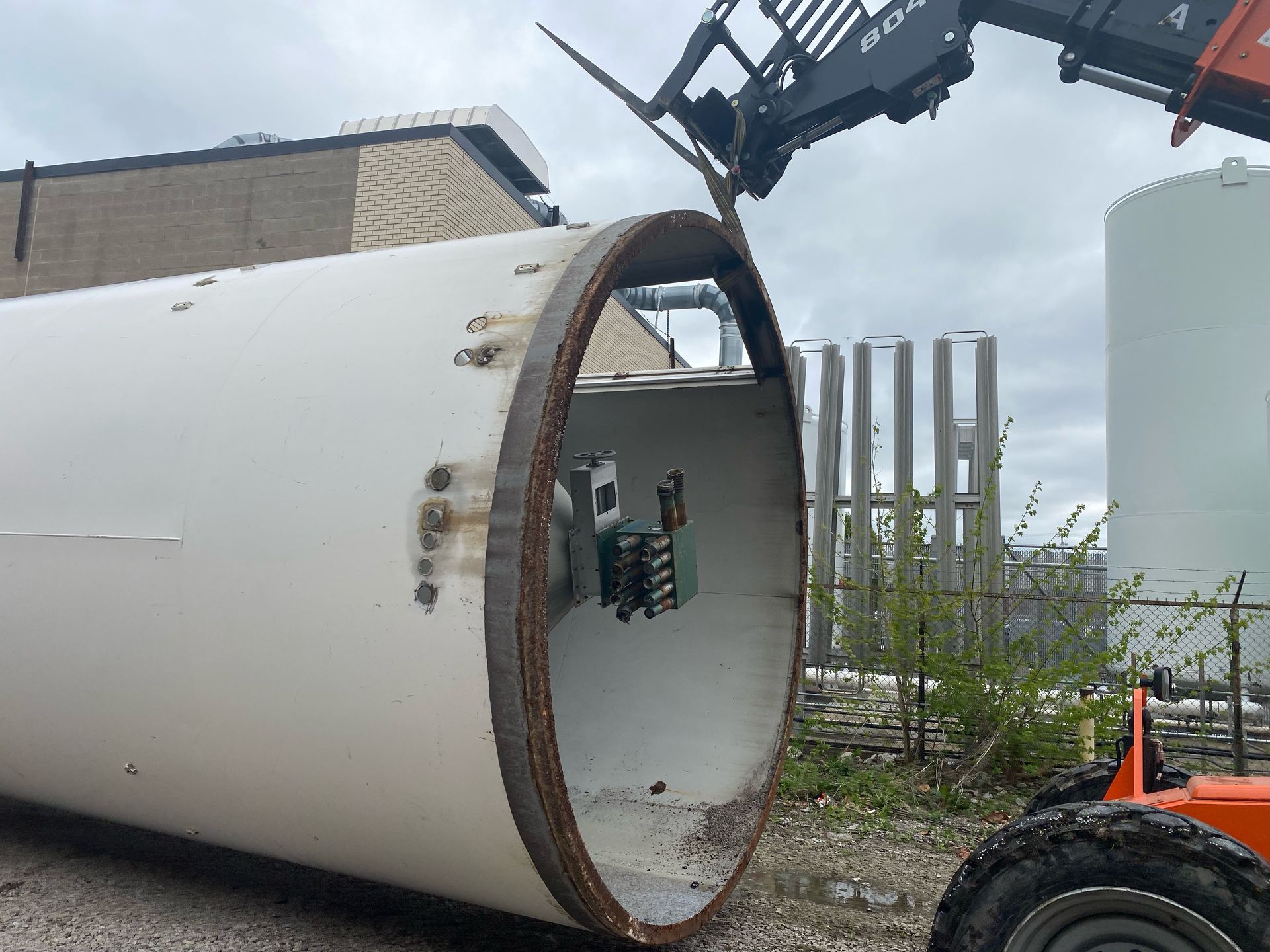 A large white pipe is being lifted by a crane.