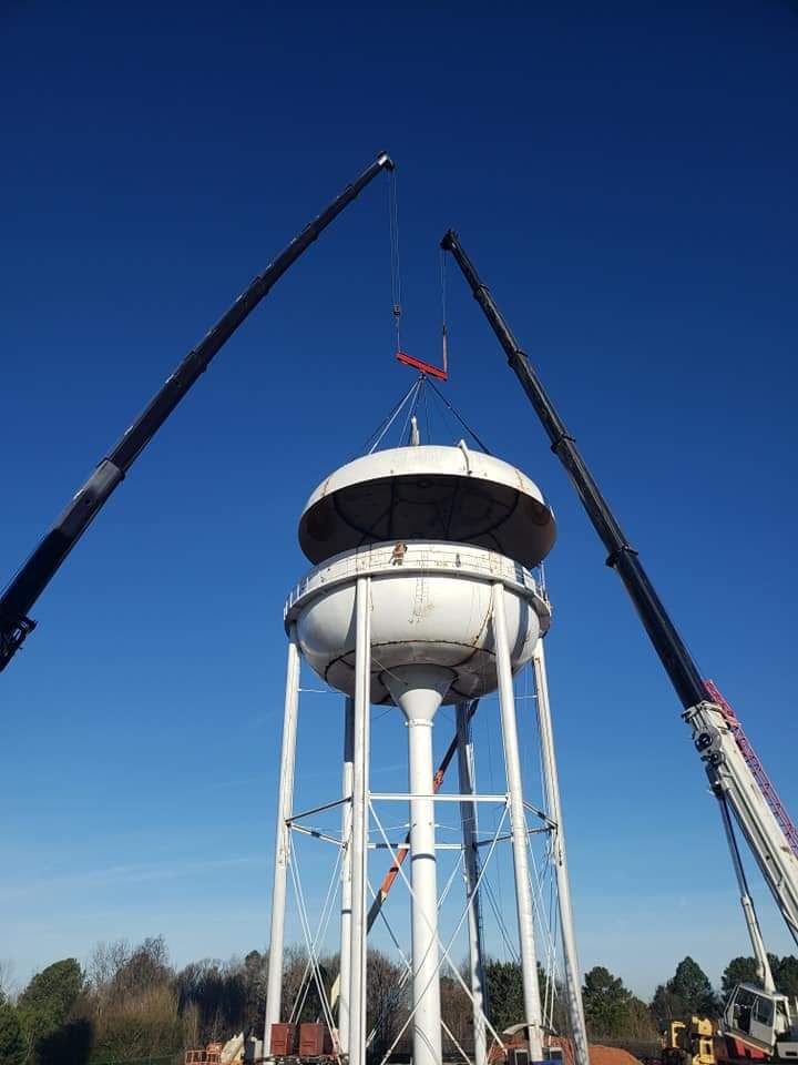 A water tower is being lifted by two cranes