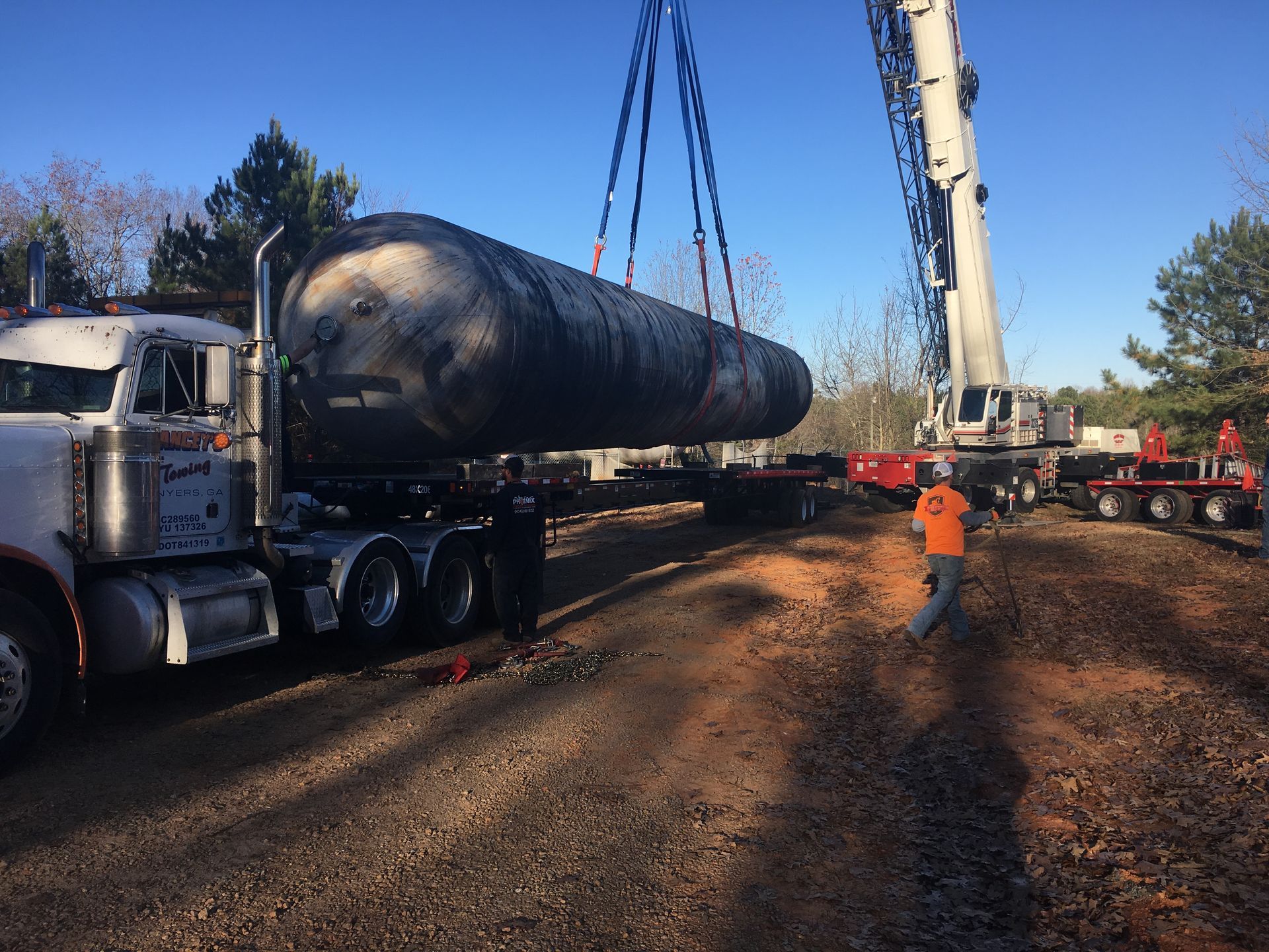 A large tanker truck is being lifted by a crane.