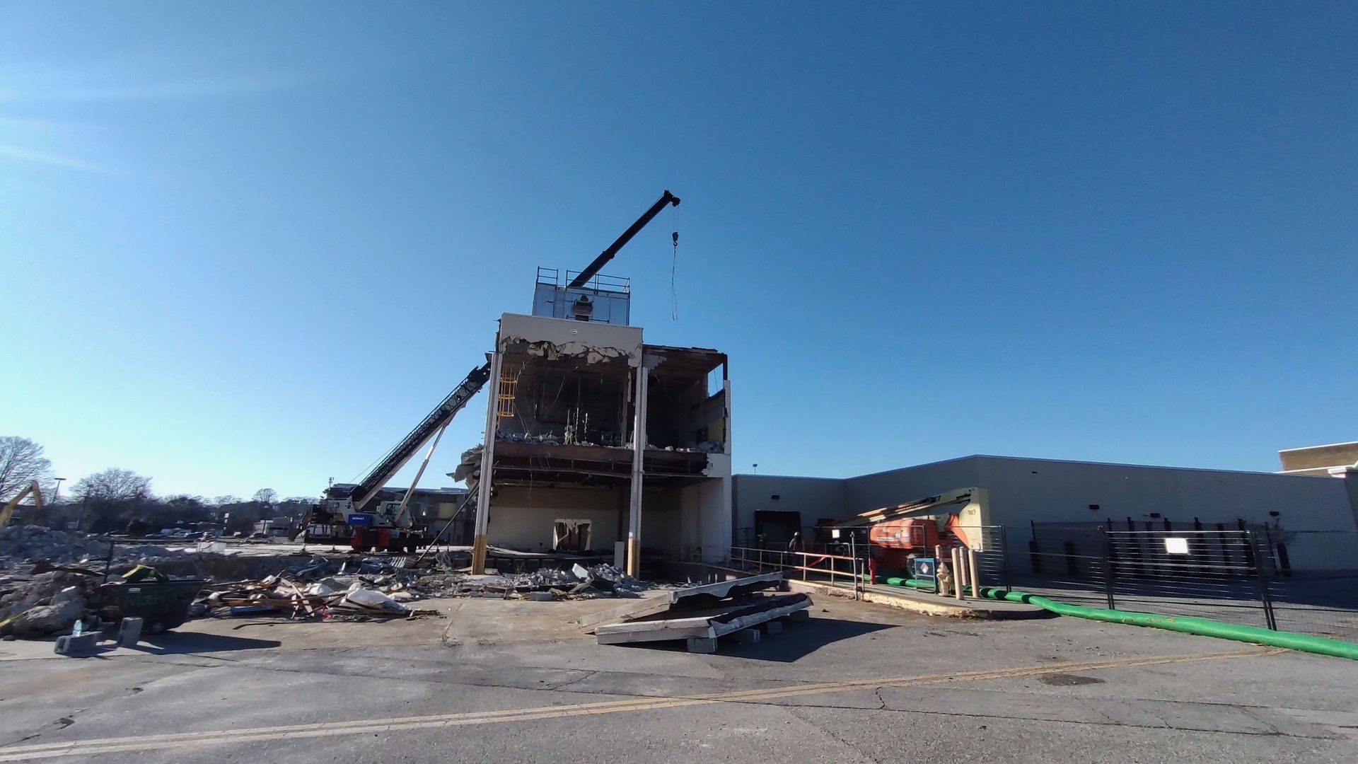 A large building is being demolished by a crane.