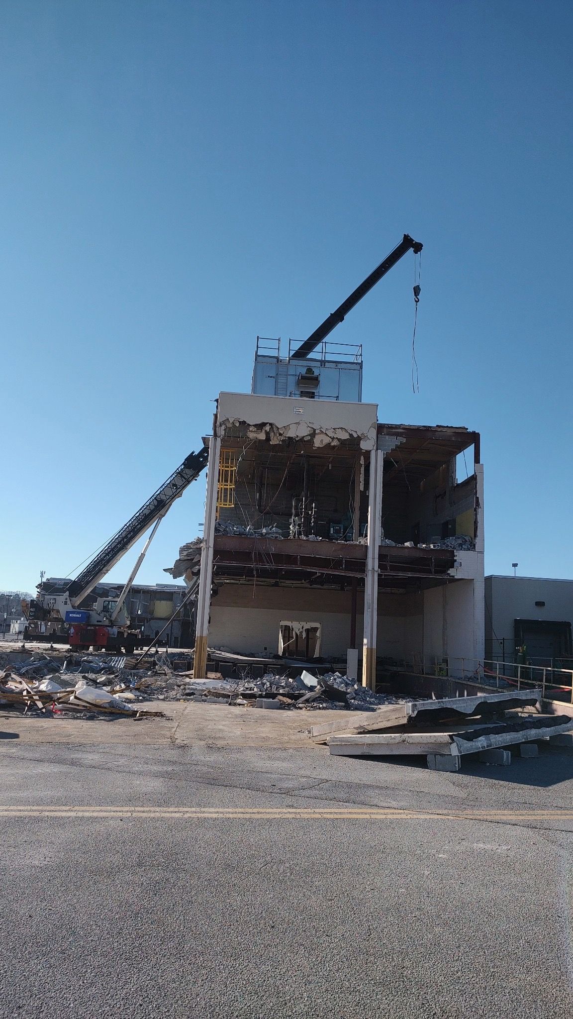 A large building is being demolished by a crane.