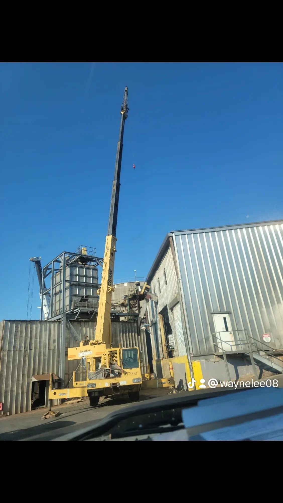 A large yellow crane is sitting in front of a building.