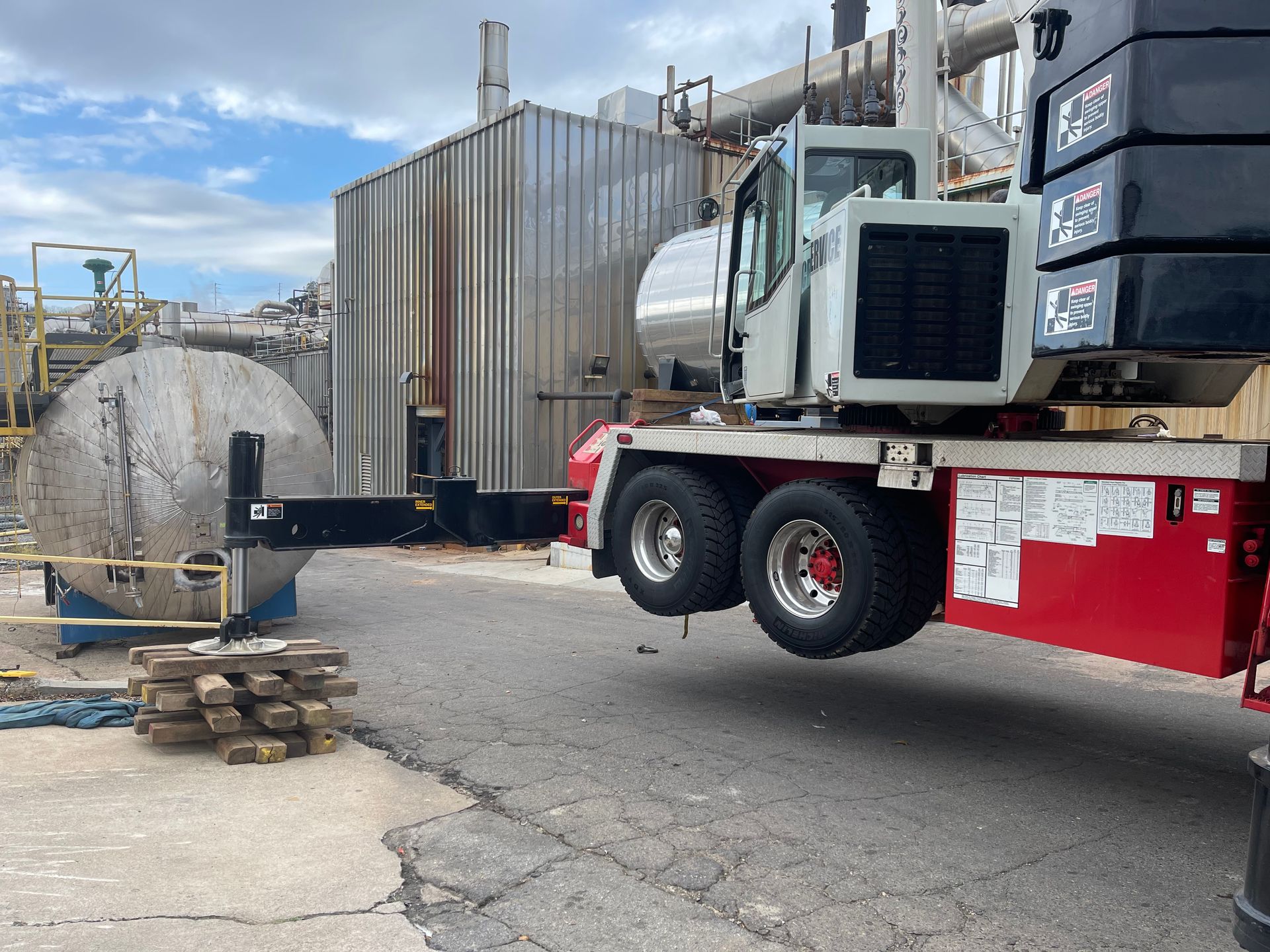 A large truck is driving down a road next to a large tank.