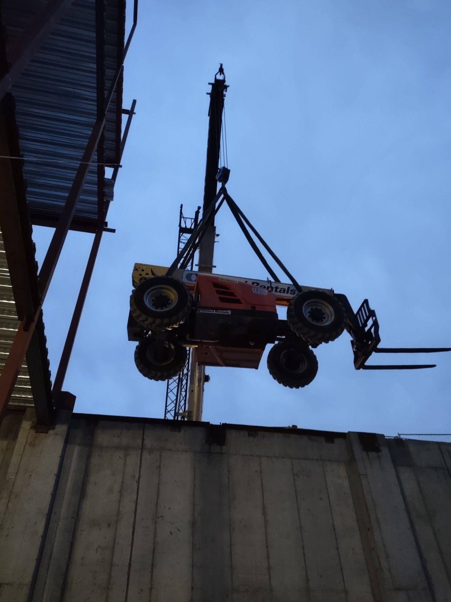 A forklift is being lifted into the air by a crane