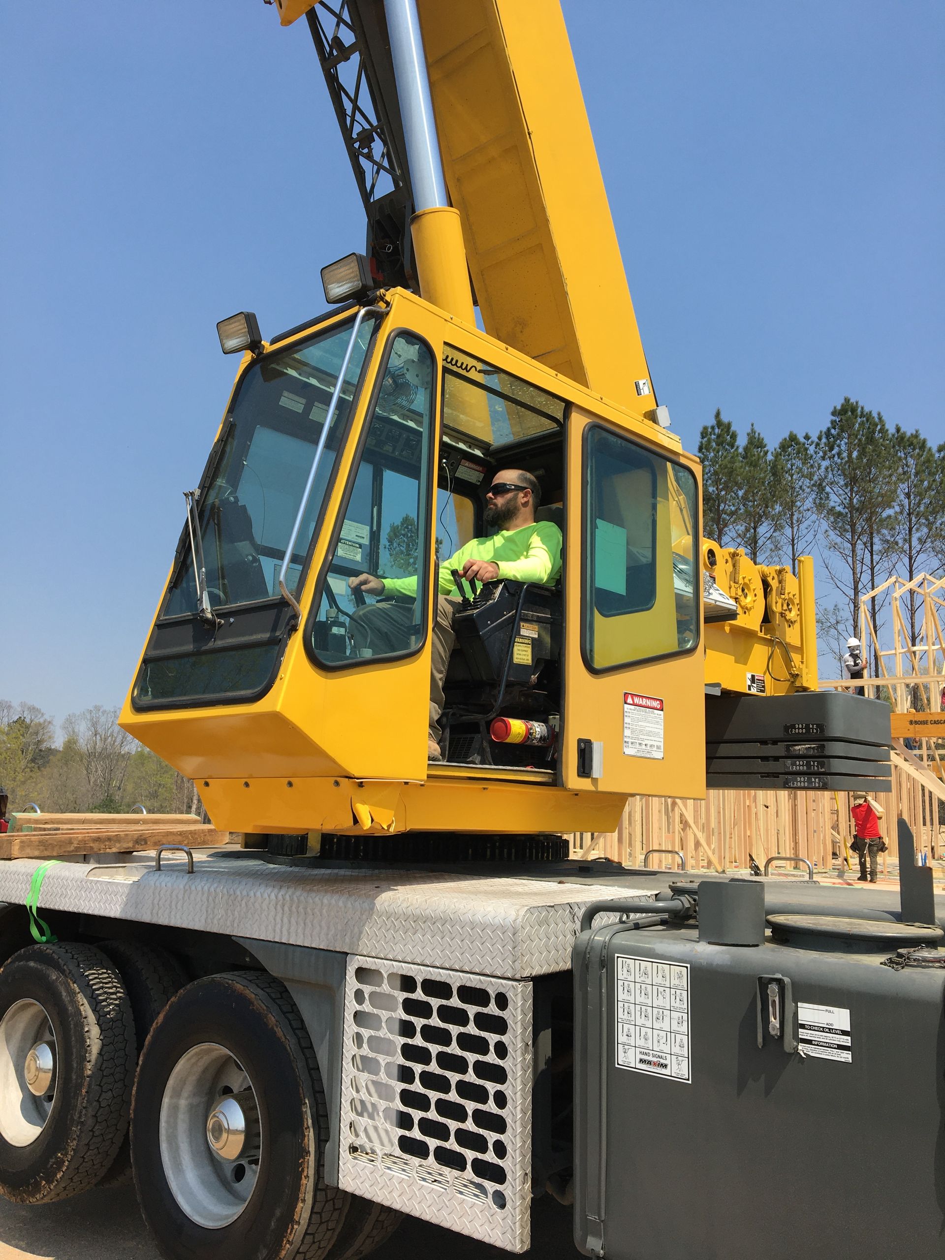 A man is driving a yellow crane on a construction site.