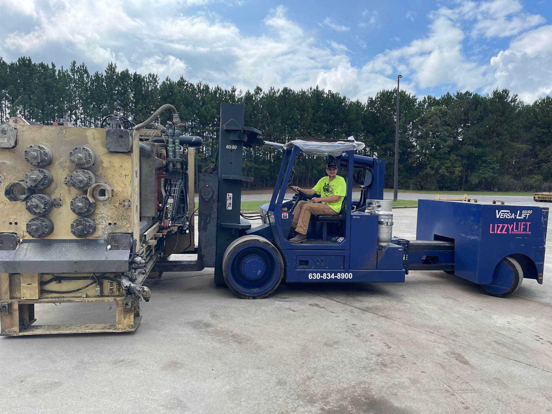 A man is driving a forklift with a trailer attached to it.