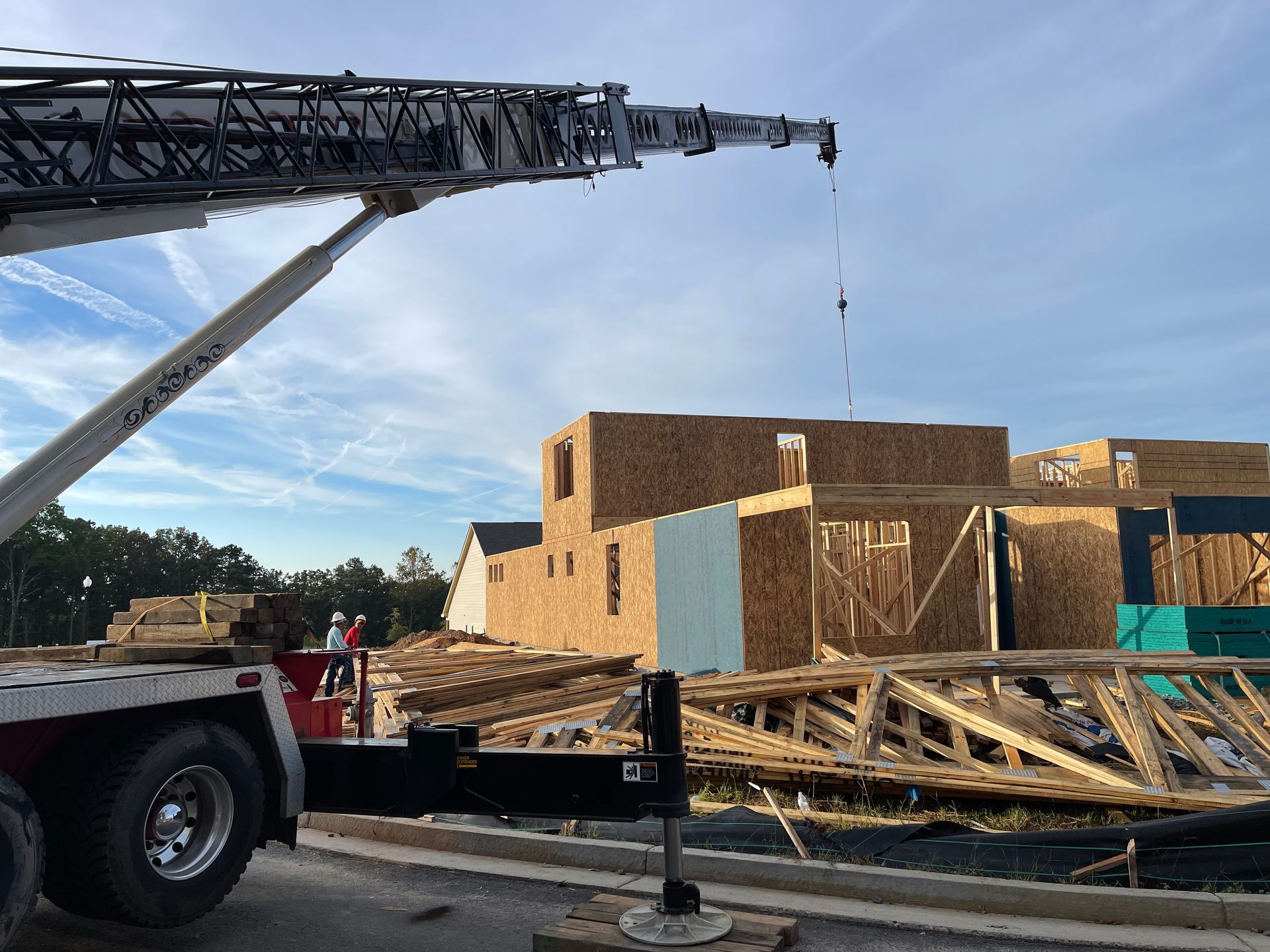 A truck with a crane attached to it is parked in front of a building under construction.