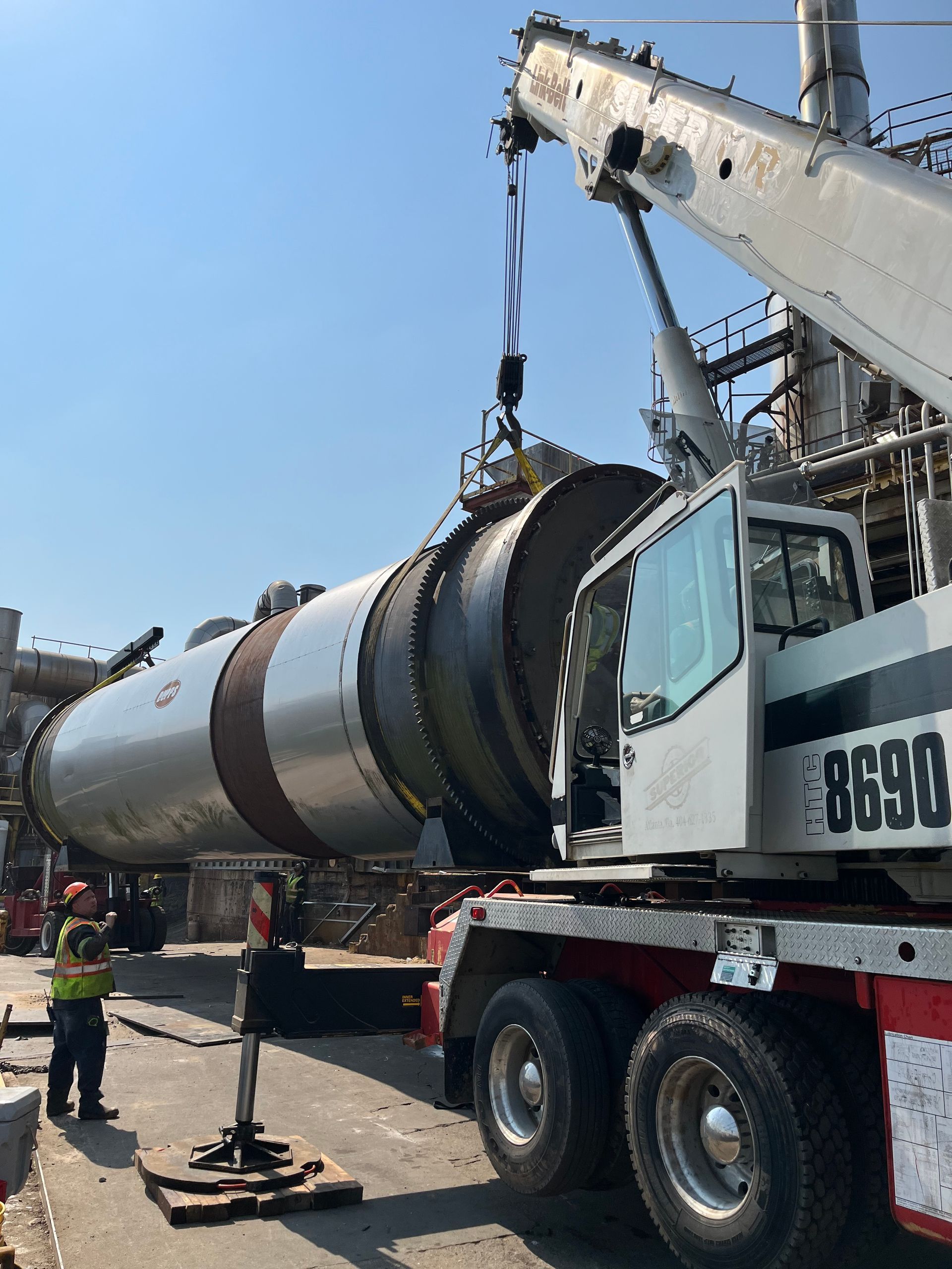 A large cylinder is being lifted by a crane on top of a truck.