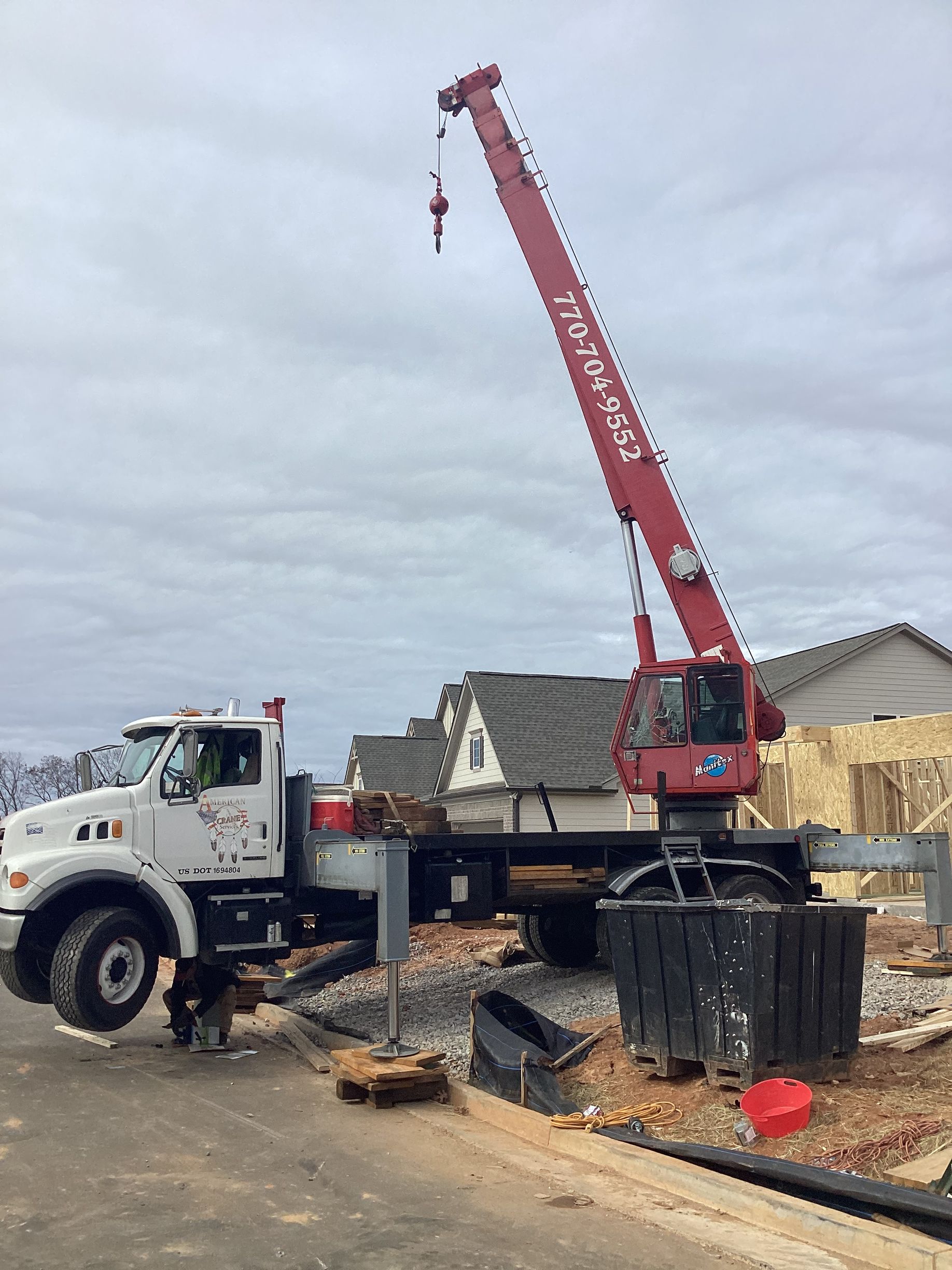 A red crane is sitting on top of a white truck.