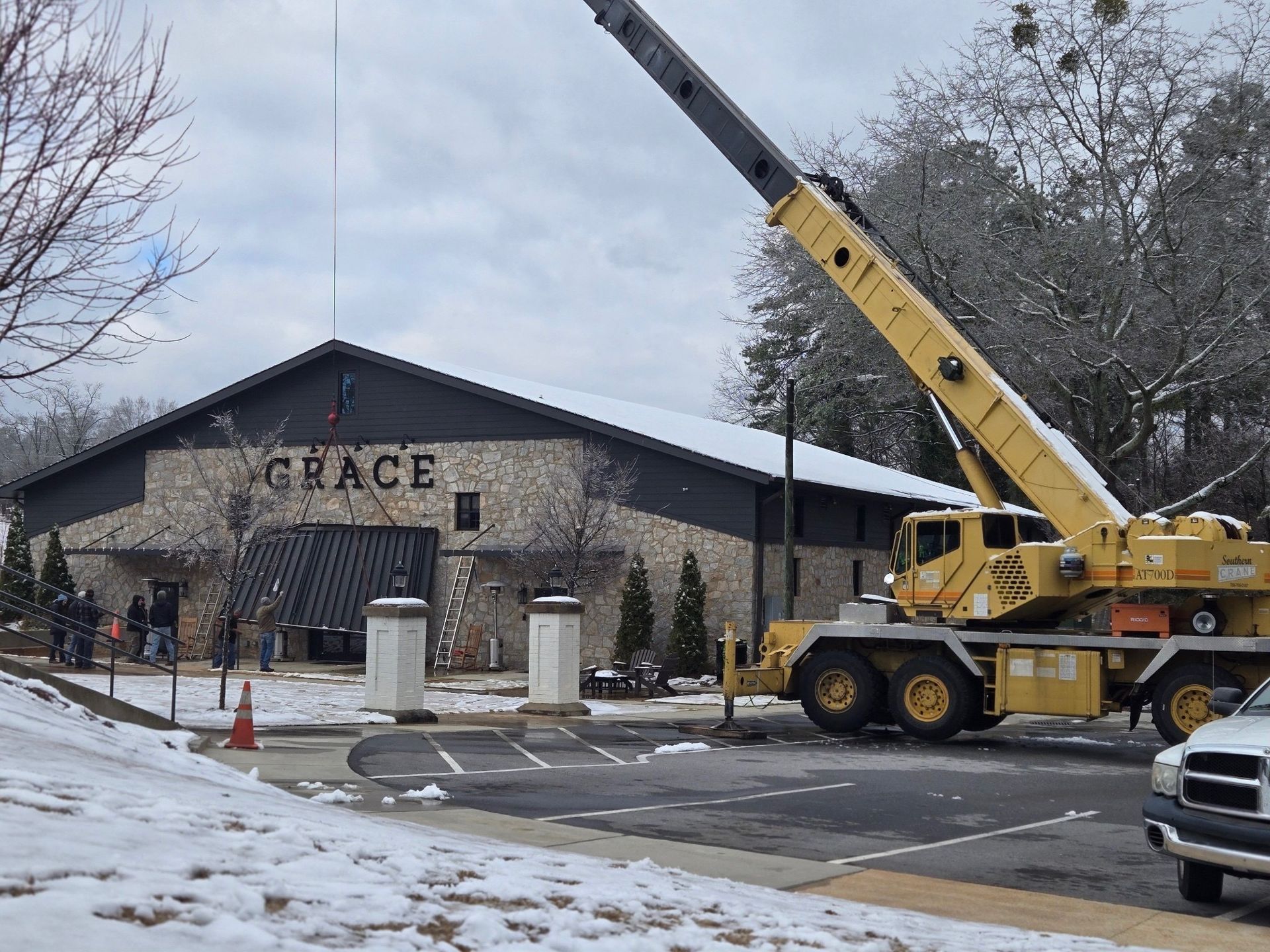 A large pipe is being lifted by a crane on a trailer.